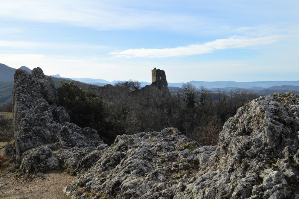 un donjon en ruine qui se détache du paysage avec des rochers au premier plan