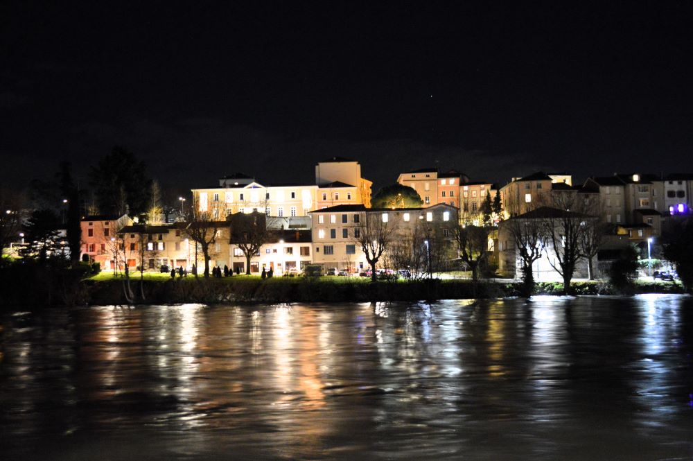une ville de nuit au bord d'une rivière en crue