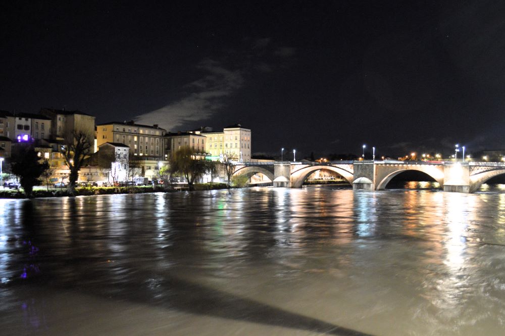 de nuit, une rivière en crue sous un pont en ville