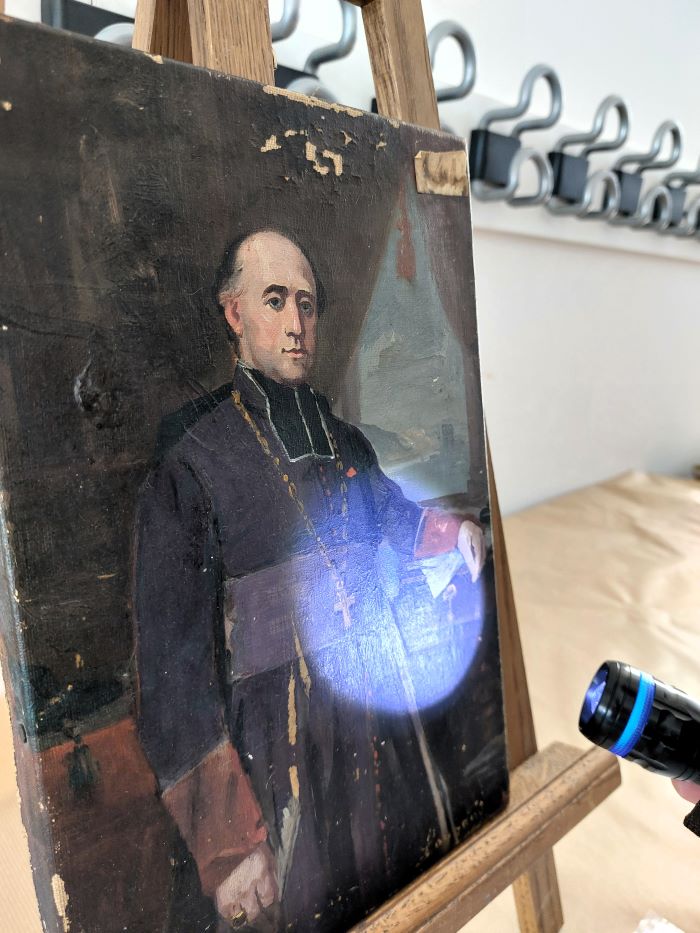un tableau abimé éclairé par une lampe UV
