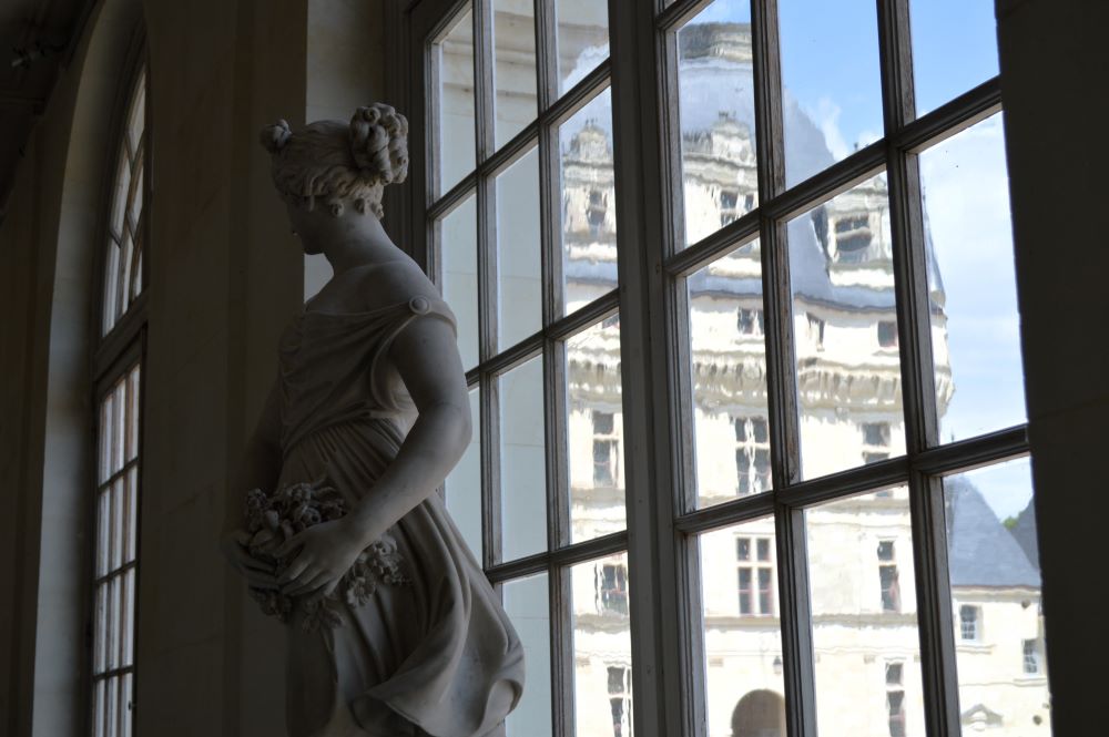 statue devant une fenêtre donnant sur une cour de château