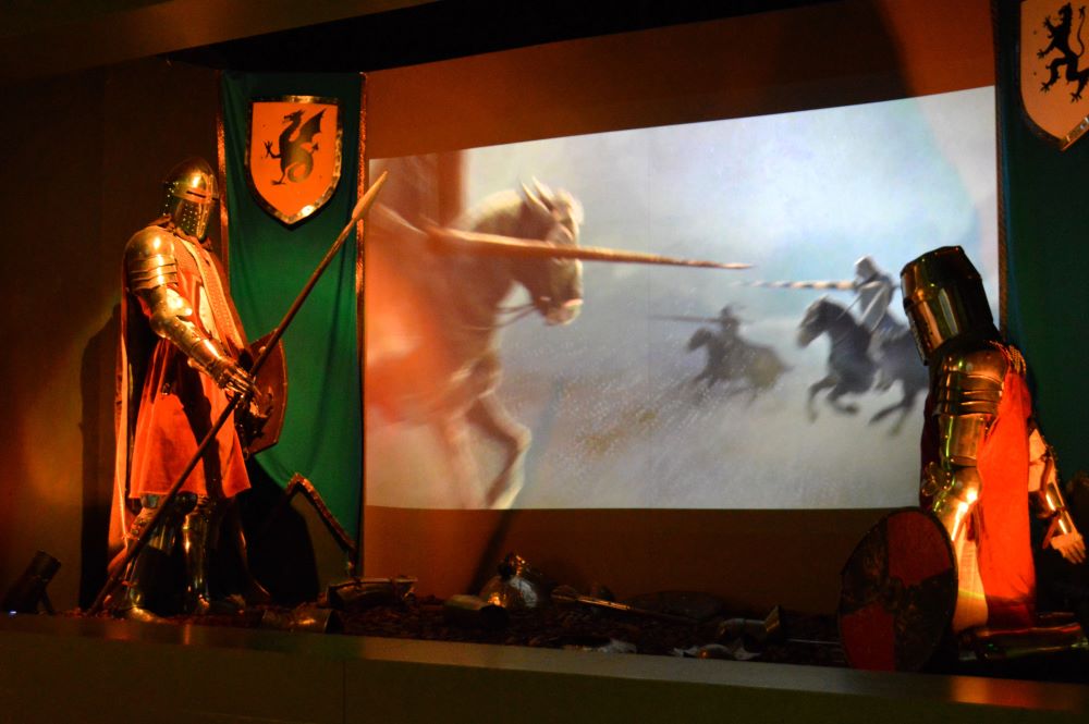 un chevalier debout tient une lance, un autre chevalier agenouillé lui fait face