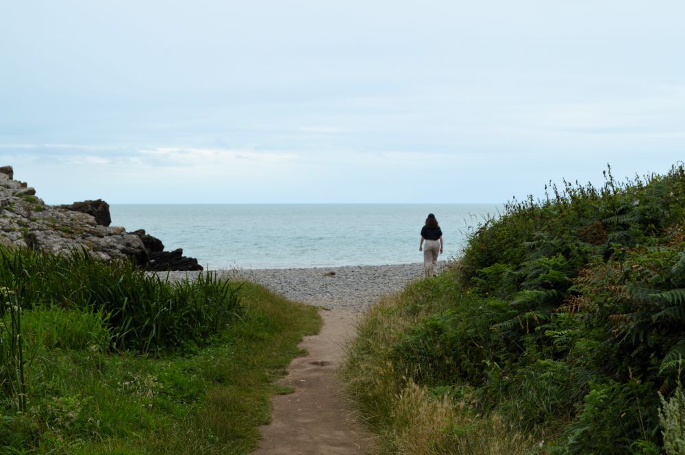 sentier débouchant sur une plage de galets