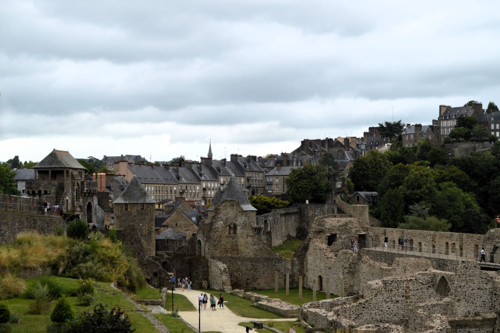 une cour de château entourée de murs et tours médiévaux, au pied d'une ville