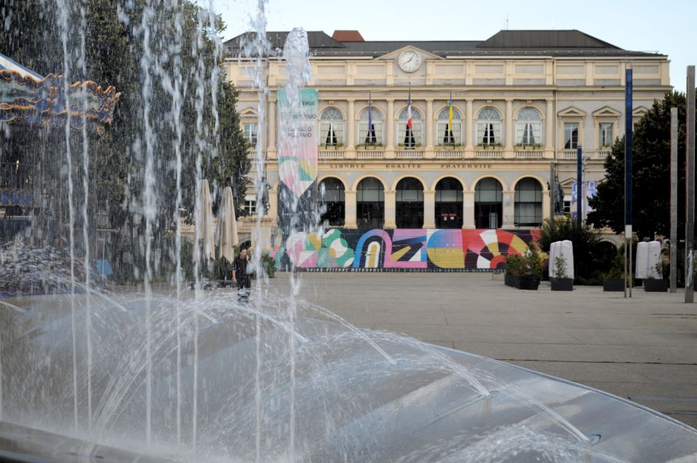 des jets d'eau au premier plan et un grand bâtiment du 19e siècle en arrière plan
