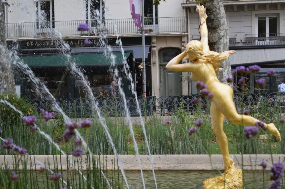 un statue dorée au milieu d'un bassin avec des jets d'eau
