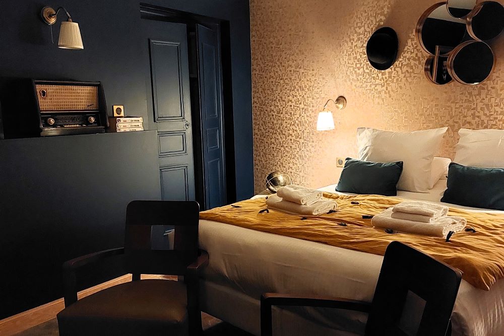 une chambre aux murs bleu foncé et doré, éclairée par une petite lampe de chevet