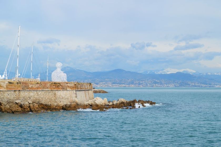 Sculpture en lettres d'acier assemblées pour former une silhouette humaine sur une jetée dans la mer