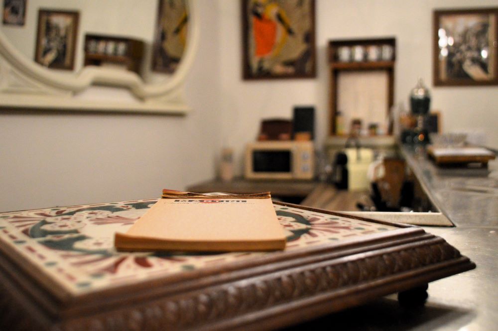 ancien carnet de prise de commande de bar-restaurant posé sur un dessous de plat vintage