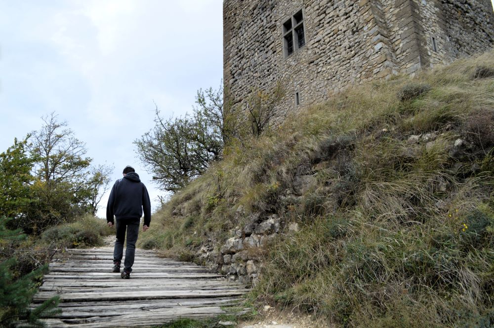 une personne traversant un pont de bois au pied d'une tour médiévale
