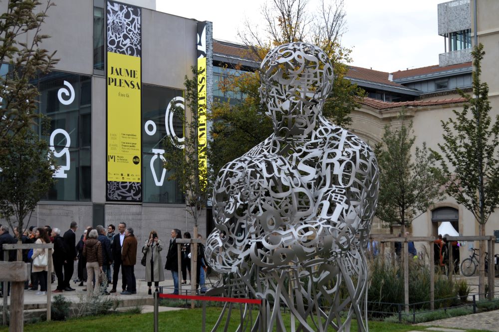 Sculpture en lettres d'acier assemblées pour former une silhouette humaine devant le musée