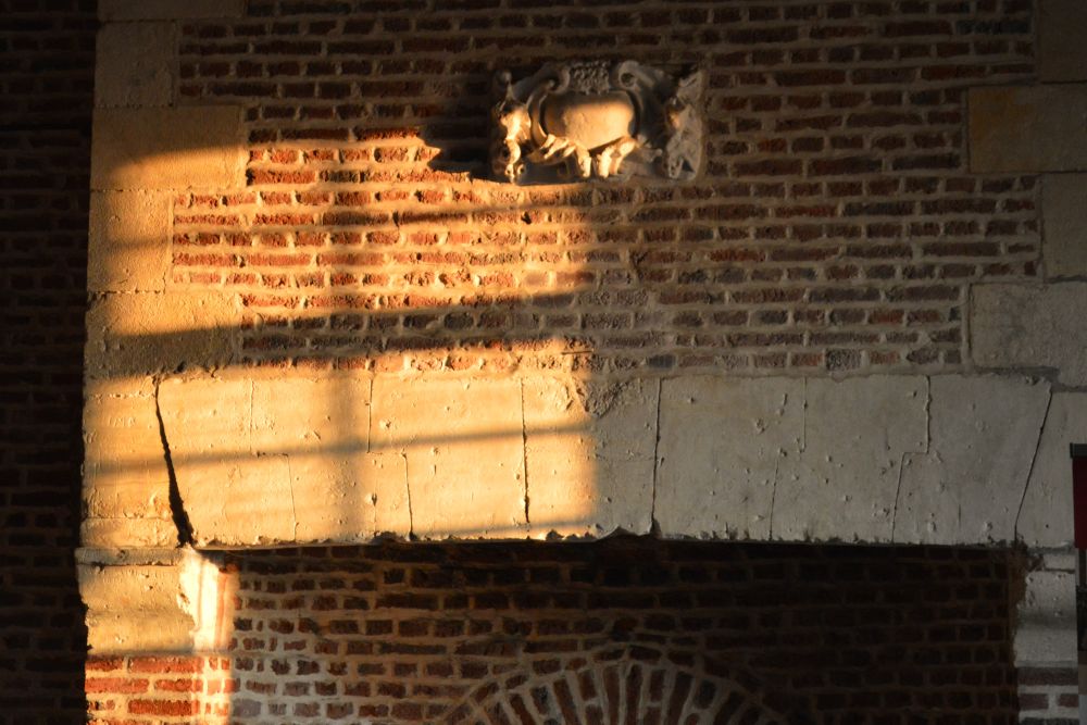 un rayon de soleil sur le manteau en briques d'une cheminée ancienne