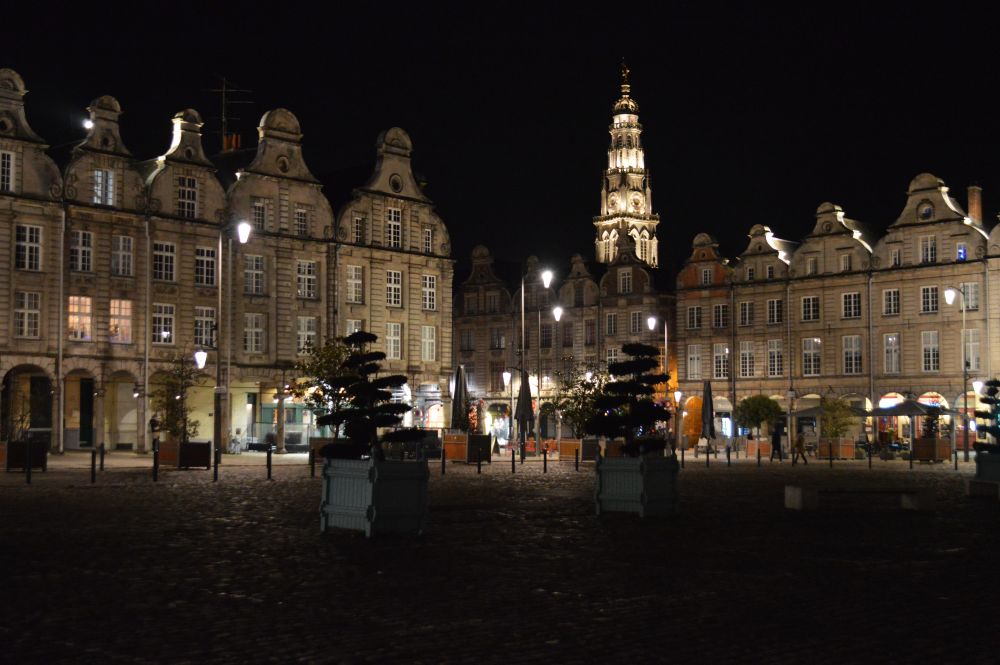 la grand place d'Arras de nuit entourée de façades baroques flamandes avec la tour du beffroi dans le fond