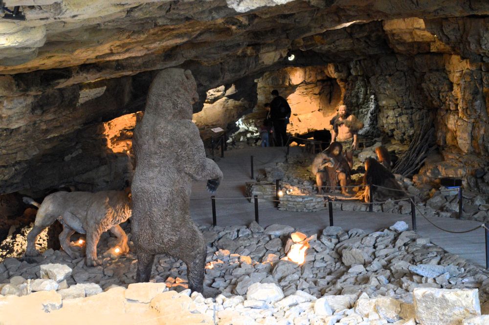 dans une grotte, on aperçoit des mannequins représentants des hommes préhistoriques ainsi qu'un ours et un lion des cavernes
