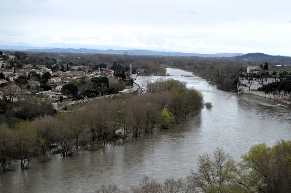 une rivière en crue entre un village et une falaise
