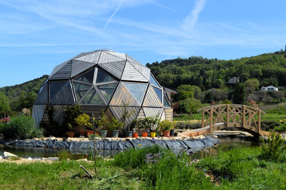 une serre géodésique à laquelle on accède par un petit pont en bois de style japonais