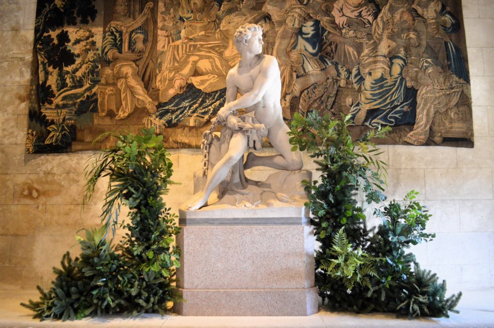 une statue inspirée de l'antiquité entourée de feuillages