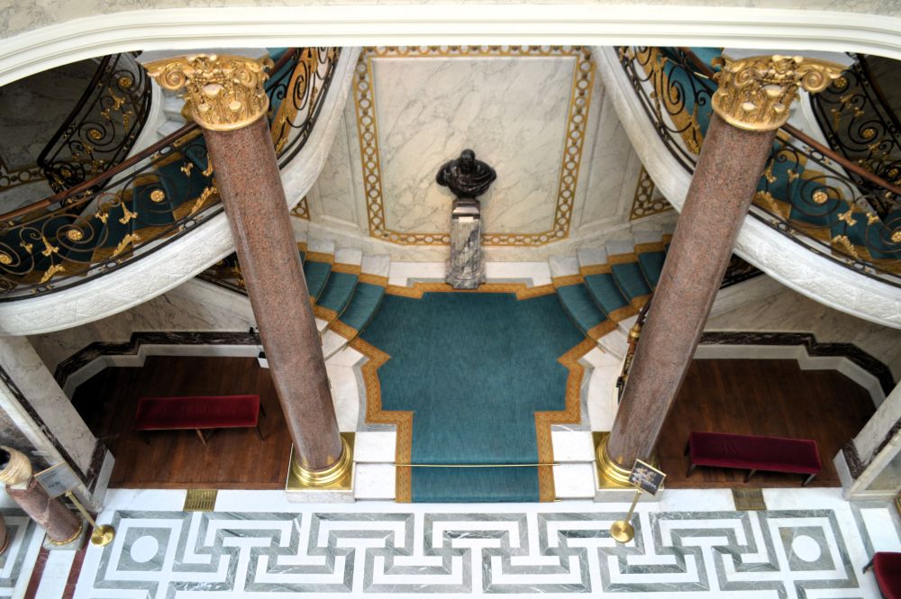 un escalier à double révolution encadré par des colonnes en marbre