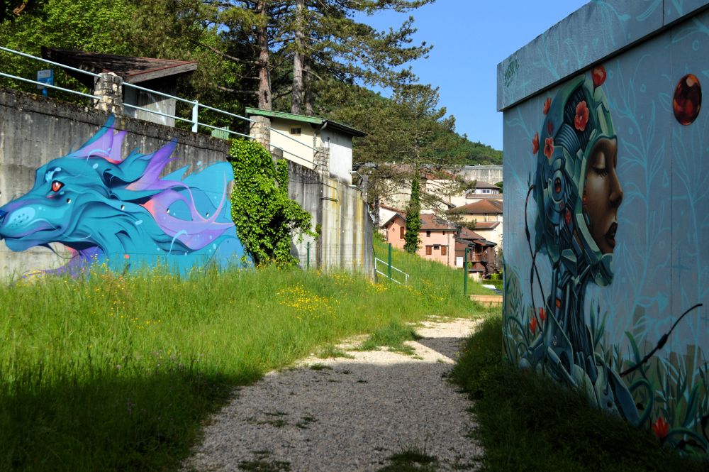 un chemin passe entre deux murs recouverts de fresques de street art 