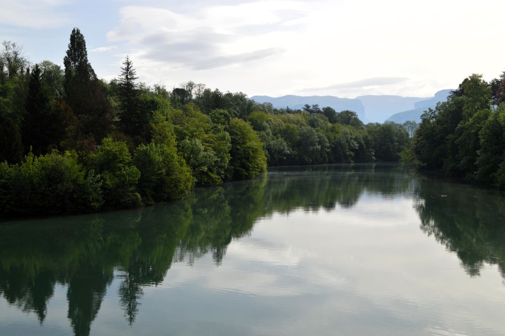 les rives boisées de la rivière s'y reflètent, et on aperçoit le Vercors dans le fond