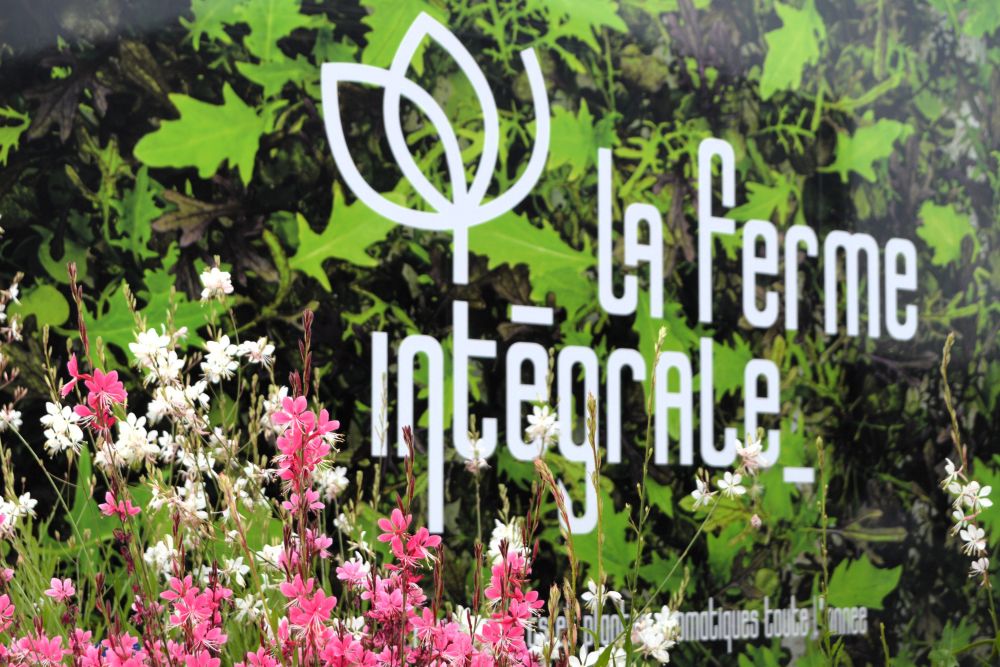 le logo de la Ferme Intégrale dans un environnement fleuri