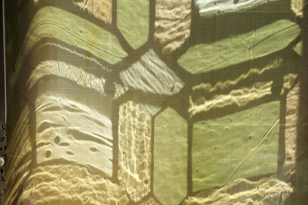 les carreaux multicolores et géométriques d'une fenêtre de la Renaissance vus à travers un voilage