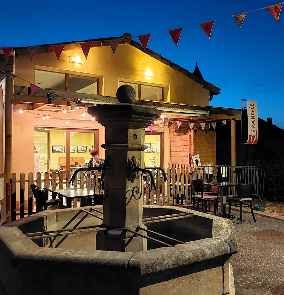 de nuit, une fontaine devant une terrasse de restaurant surmontée de guirlandes de fanions