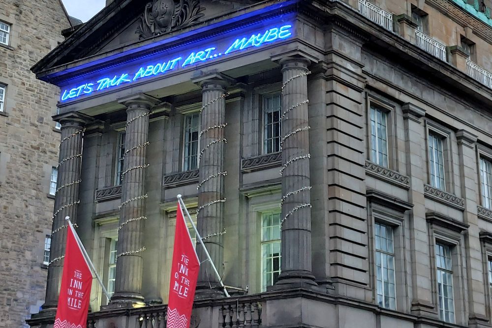 bâtiment avec en lettres lumineuses la phrase Let's talk about art... maybe