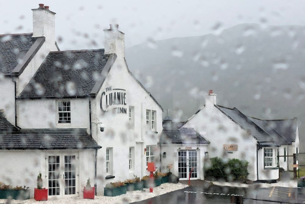 L'auberge Loch Cluanie Inn à travers une fenêtre pleine de gouttes de pluie