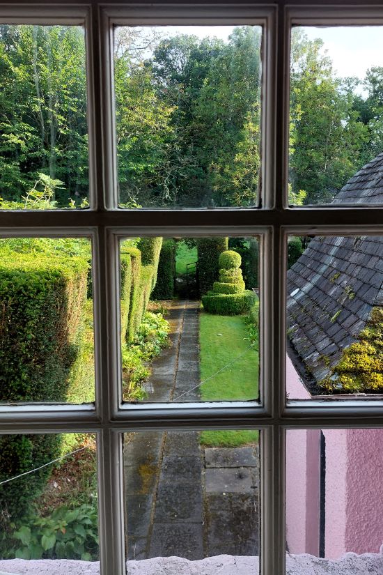 un jardin avec des topiaires vu à travers la fenêtre.