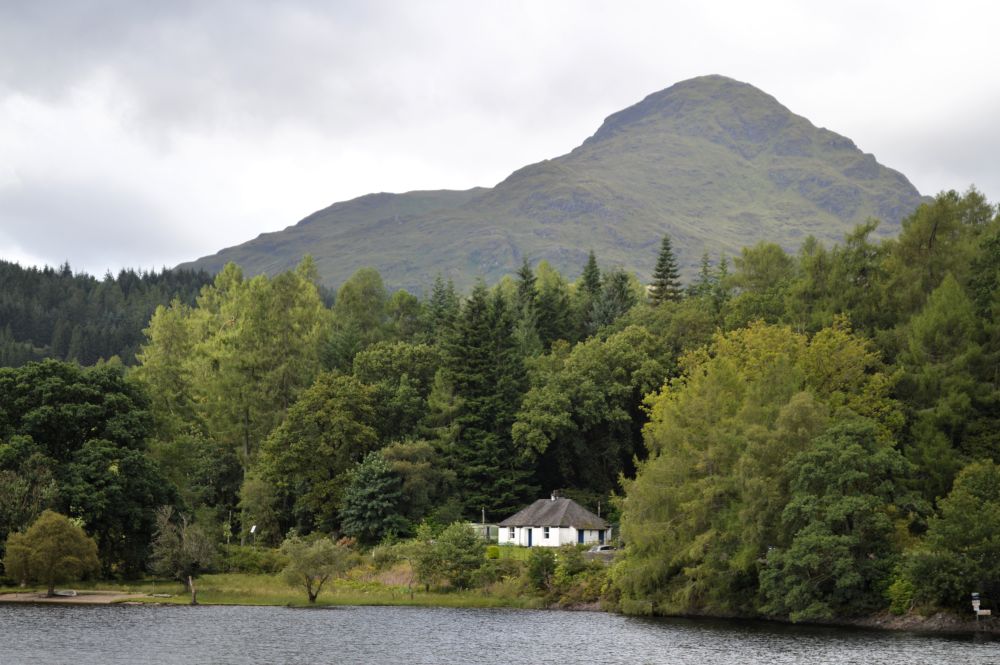 une maison blanche au pied d'un montagne et au bord d'un lac en Ecosse