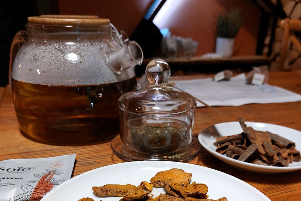 infusion Caravane d'OR dans une théière en verre, petite cloche en verre, cannelle et curcuma sur des asssiettes