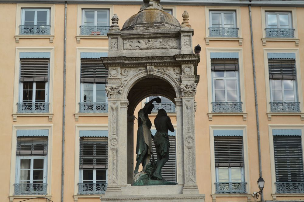 fontaine de la Renaissance représentant le baptême de Jésus avec une façade lyonnaise typique en arrière plan