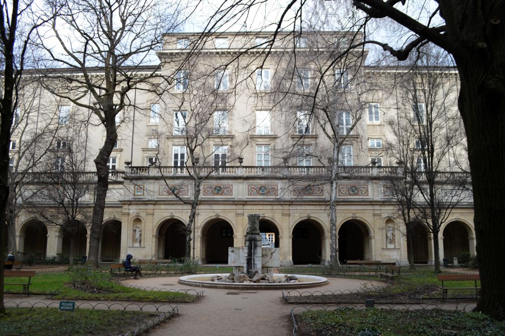 un jardin devant un bâtiment bordé d'arcades