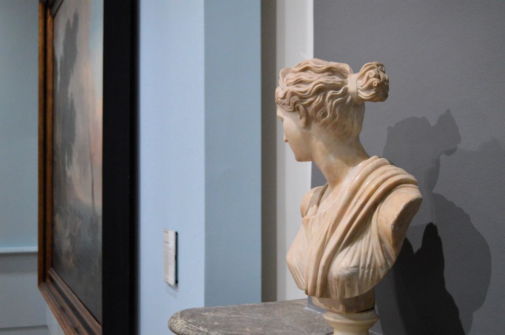 une sculpture de buste posée sur un manteau de cheminée, le regard tourné dos au visiteur